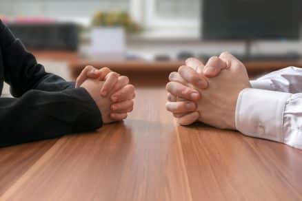 Two businesspeople sitting across from each other renegotiating.